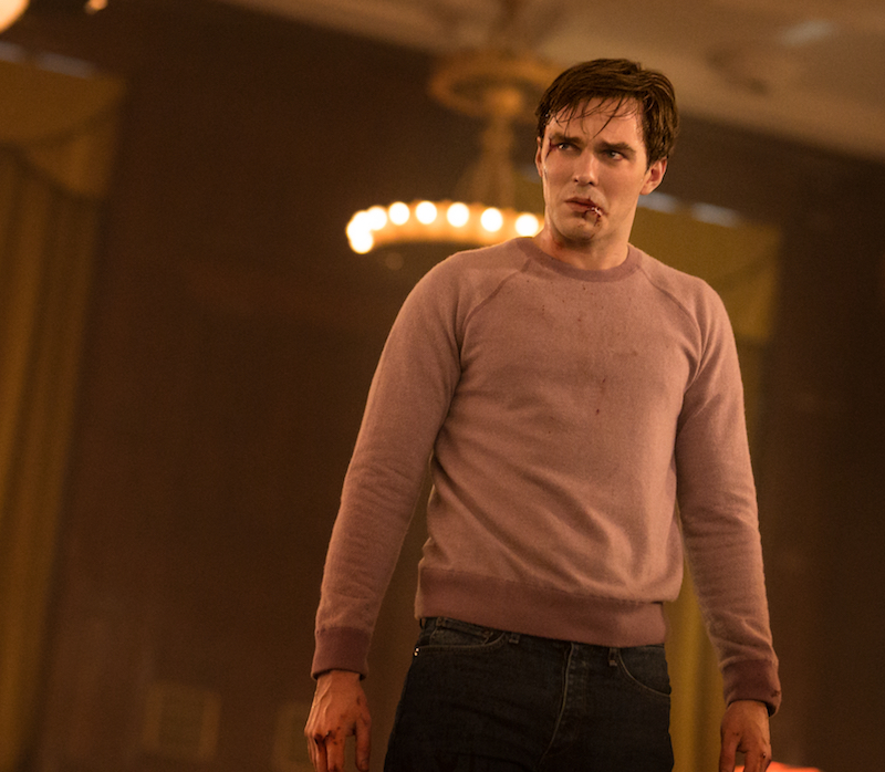 Renfield olha assustado. Ele usa uma blusa de manga longa rosa e tem sangue na boca e nas mãos.