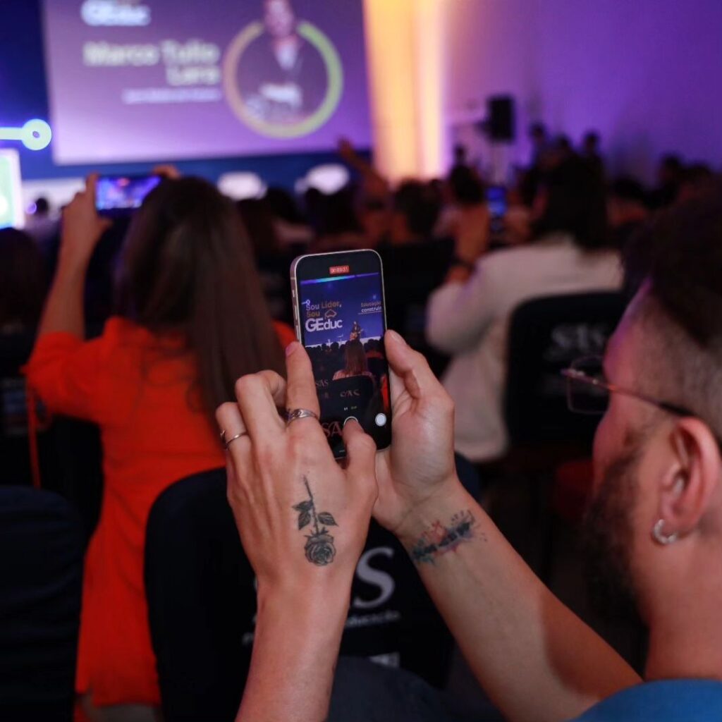 Homem tira foto com o celular de palestra do congresso GEduc 2024.