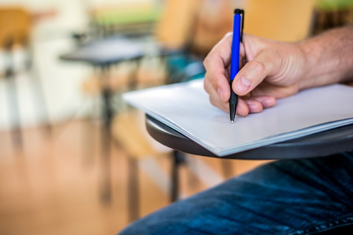 Plano de uma mão escrevendo em um caderno com uma caneta