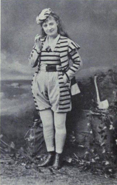 Lydia Thompson vestida de Ganem, com macacão listrado e botas de couro