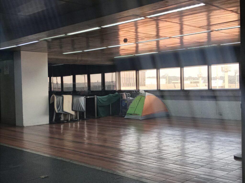 Barraca dos refugiados nas cores verde e laranja no meio do saguão do Aeroporto de Guarulhos