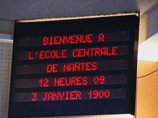 Placa digital exibindo: "Bienvenue à l'École Centrale de Nantes, 12 heures 09, 3 janvier 1990"