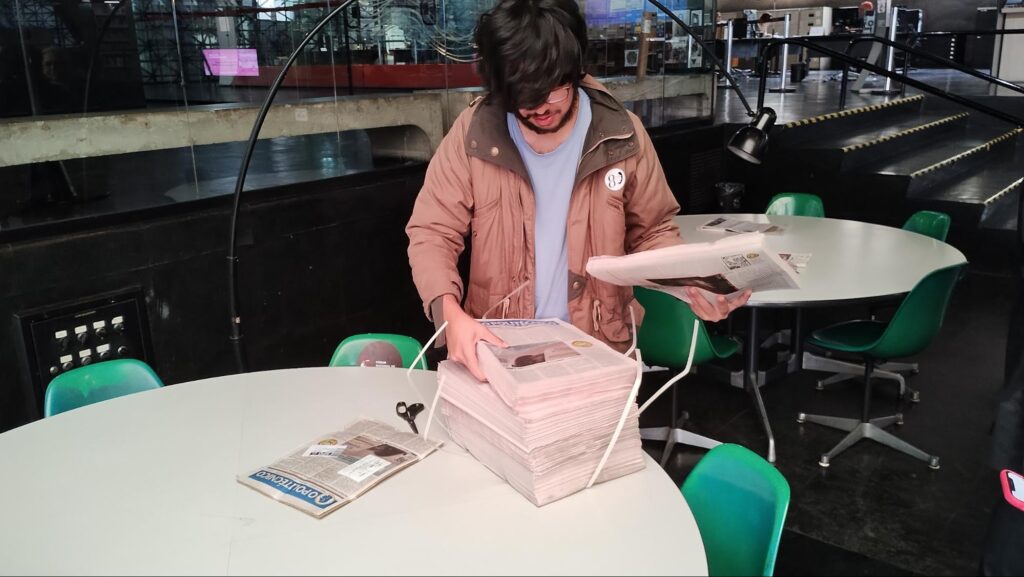 Homem interage com pilha de exemplares do jornal O Politécnico