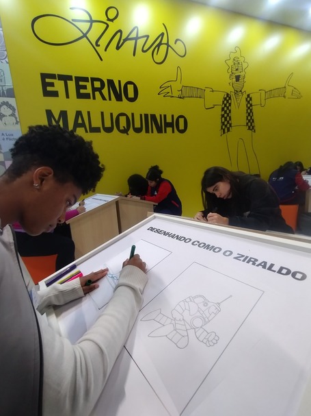 Menino desenha em estande que homenageia Ziraldo.