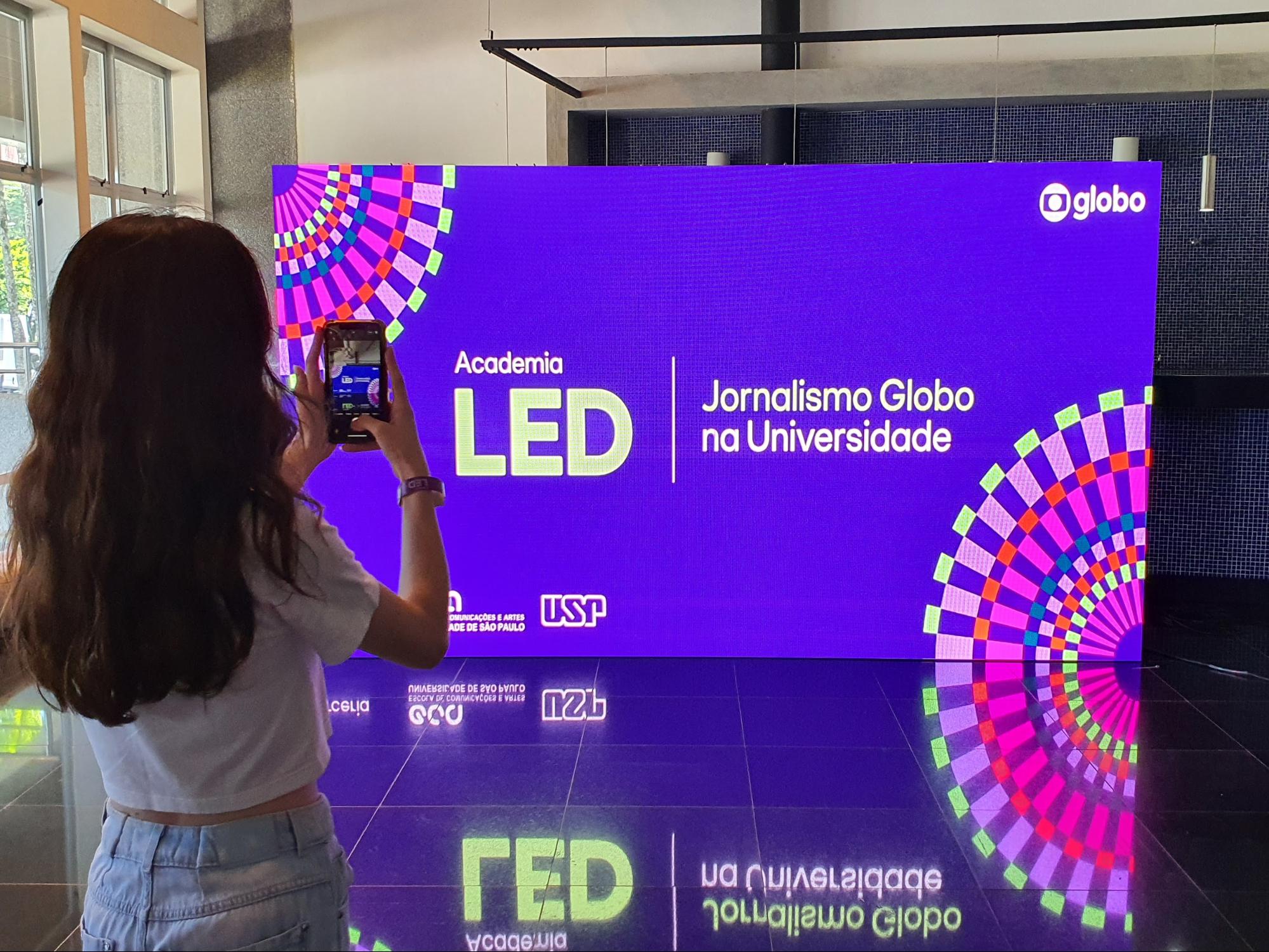 Estudante no evento de lançamento na Academia LED da Rede Globo tirando foto para compartilhar nas redes sociais