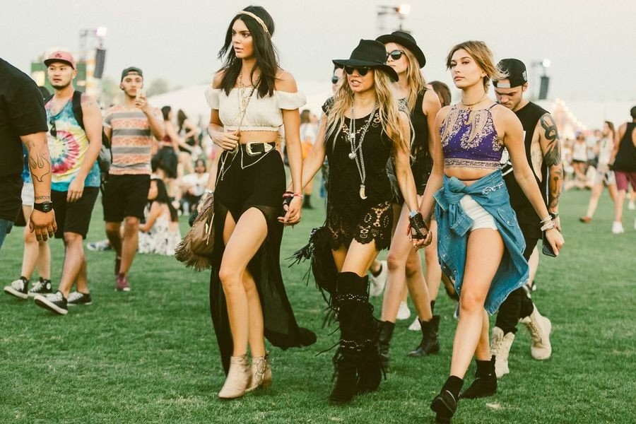 Três mulheres usando roupas no estilos boho, caminhando em um festival
