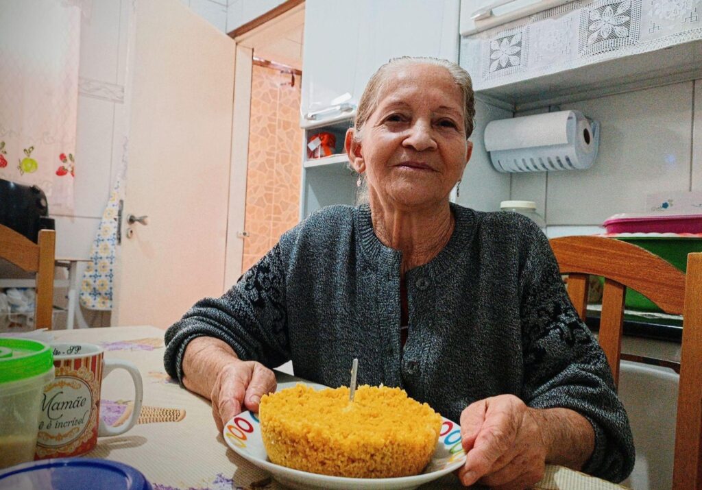 Idosa mostra o cuscuz que cozinhou.
