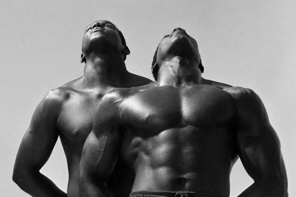 Dois homens negros sem camisa, ambos olhando para cima. Imagem em preto e branco