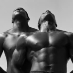 Dois homens negros sem camisa, ambos olhando para cima. Imagem em preto e branco