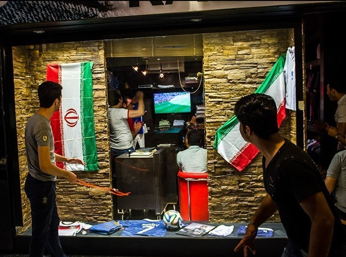 Torcedores assistindo jogo do Irã em um local com bandeiras do país