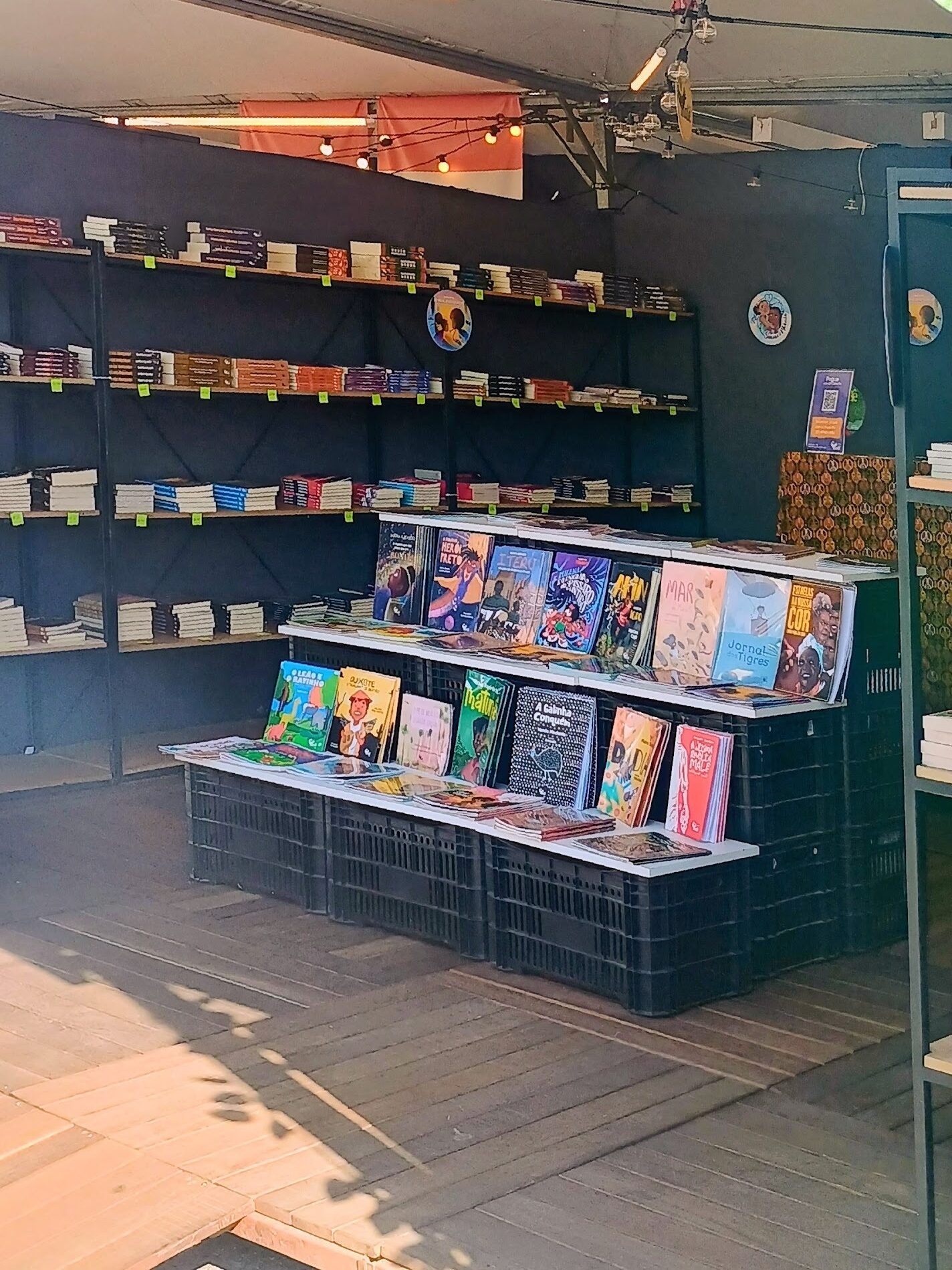 Livros infantis dispostos em caixotes e prateleiras no tablhado literário da Feira do LIvro 2026