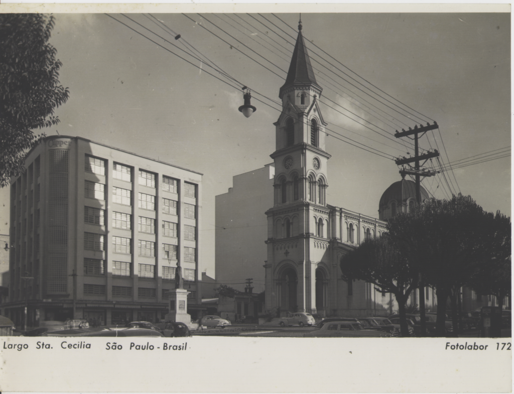 A foto mostra a Loja Clipper, localizada em São Paulo. O Prédio é retangular e se lolcaliza no Largo da Santa Cecília, ao lado de uma construção que parece uma igreja advinda de uma arquitetura gótica