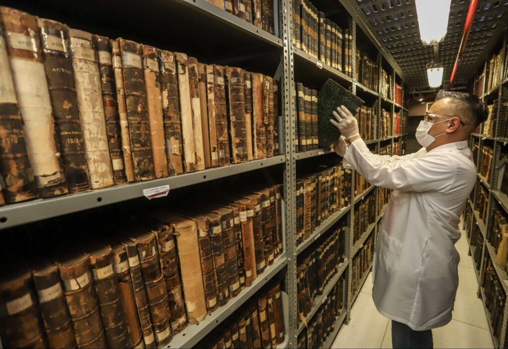 Homem manejando com luvas livros de acervo histórico