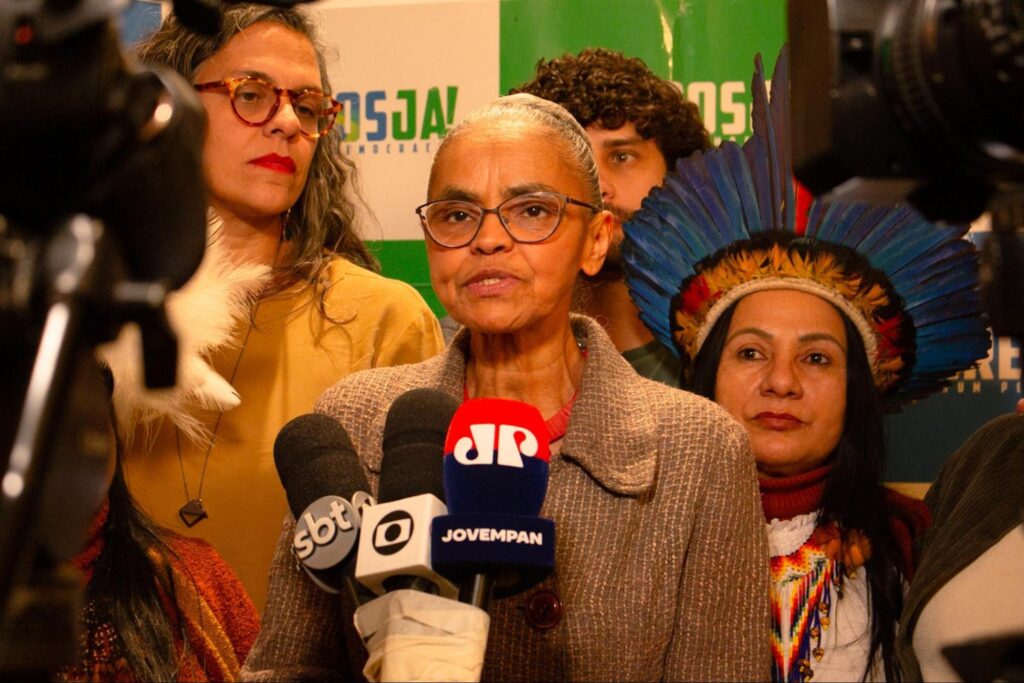 Marina Silva sendo entrevista por jornais com miccrofones na frente