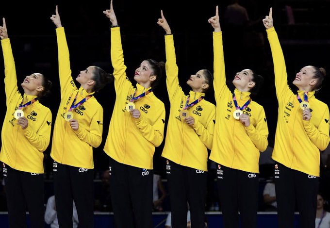 Imagem da seleção brasileira de ginástica rítmica feminina vestindo as medalhas de ouro e apontando para cima