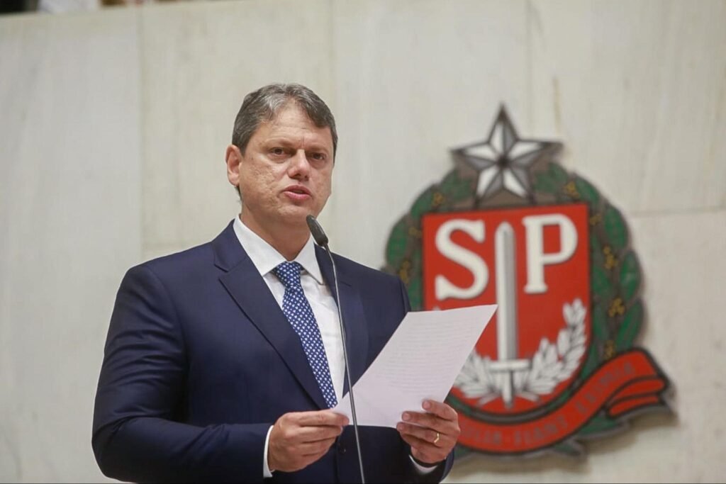 Homem branco de terno azul falando ao microfone