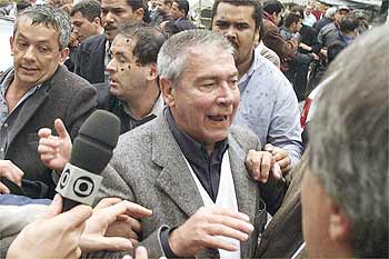 Foto de homem sendo entrevistado em meio a uma multidão.