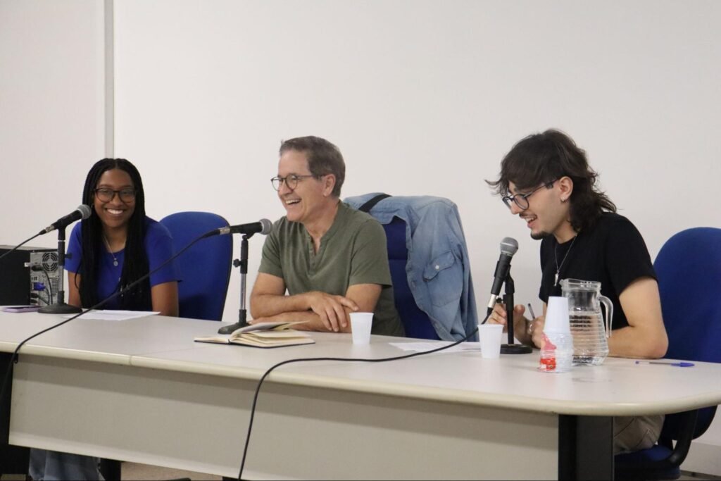 Foto de três pessoas sentadas em uma mesa.