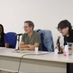 Foto de três pessoas sentadas em uma mesa.