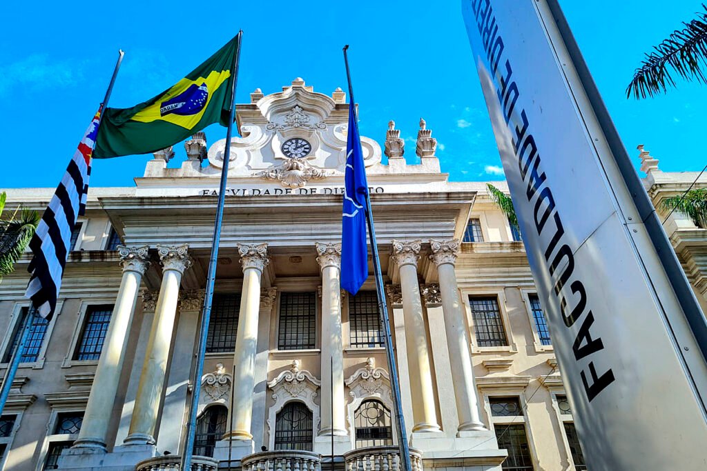 Prédio branco com arquitetura antiga com bandeiras na frente