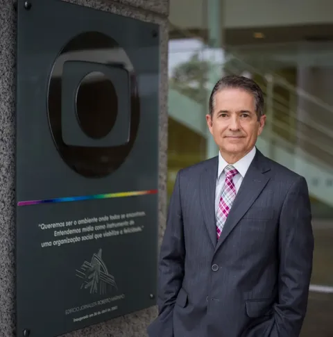 Foto de Carlos Trsmontina enfrente ao símbolo da Globo.