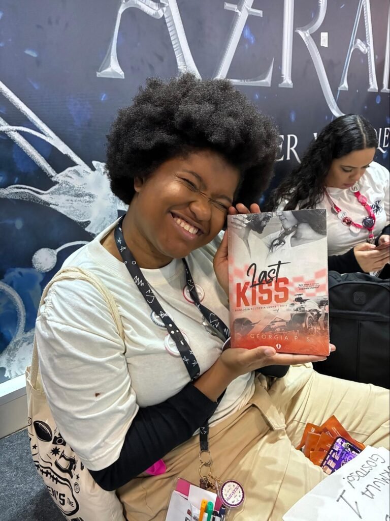Leitora sorridente segura o livro Last Kiss no espaço de autores independentes da Bienal do Livro.