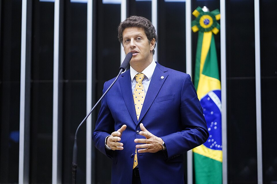 Homem branco de terno azul falando no microfone