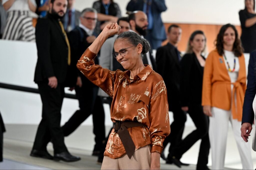 Mulher negra de coque com blusa laranja sorrindo