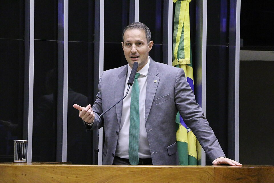Homem branco de tenro cinza falando ao microfone