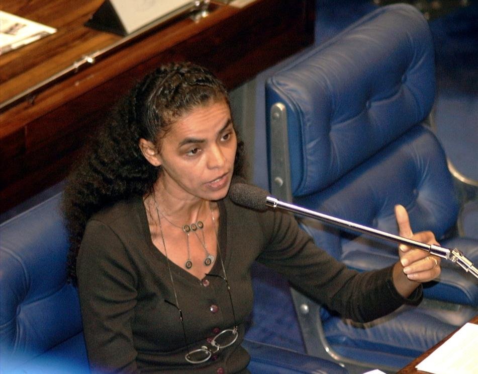 Mulher negra de blusa preta falando ao microfone