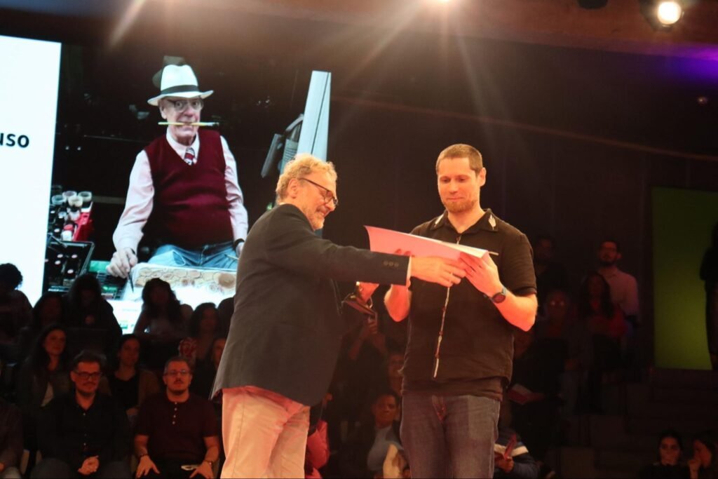 Dois homens brancos com roupa preta no palco