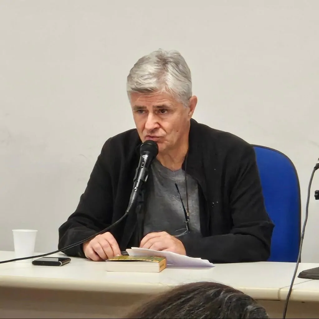 Homem apoia as duas mãos na mesa.