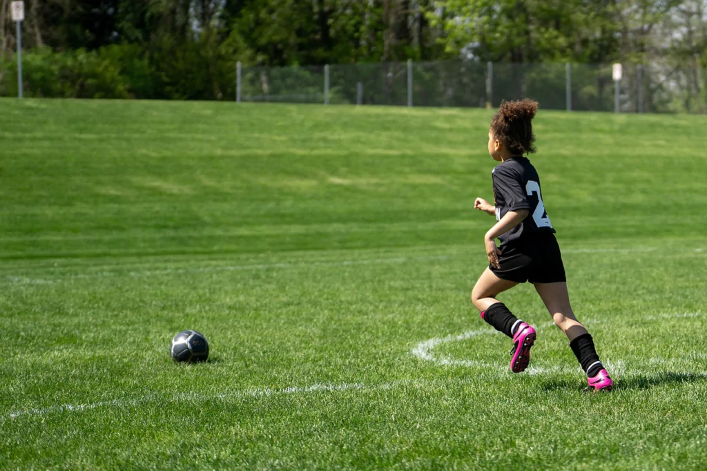 Menina jogando futebol em um dia ensolarado