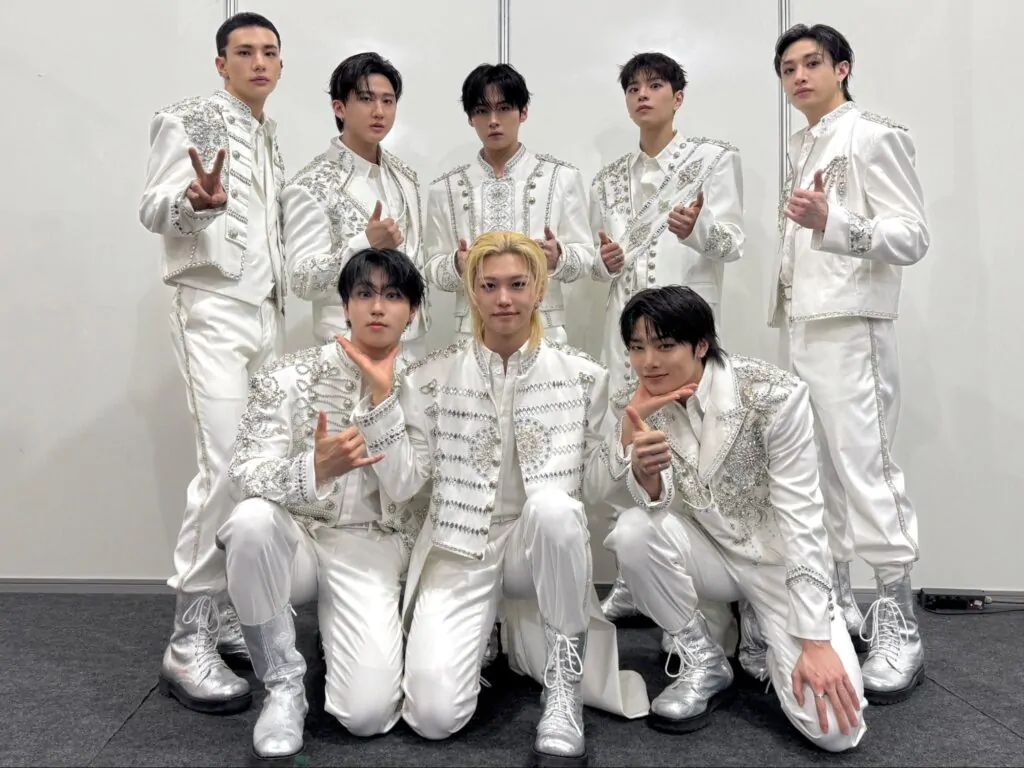 Membros do Stray Kids em figurinos brancos.