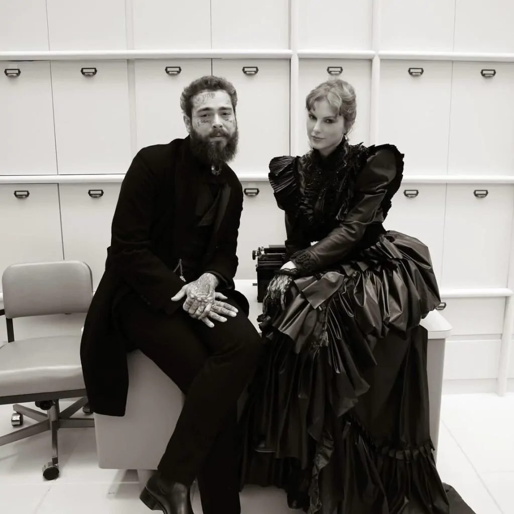Os cantores Post Malone e Taylor Swift aparecem sentados em uma mesa. Ao fundo, estão gavetas de um amário, uma cadeira de escritório na esquerda e a foto está em preto e branco. Post Malone usa uma roupa formal e inteiramente escura. Taylor utiliza um vestido totalmente fechado e também escuro, no estilo próximo ao da estética rococó. Ela também usa uma luva de renda e, atrás da cantora, há uma máquina de escrever.