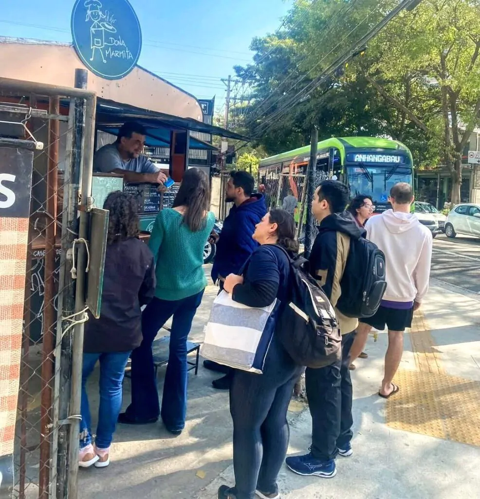 Trailer do Dona Marmita, Leonardo aparece vendendo as marmitas e uma fila de pessoas aguarda seus almoços.