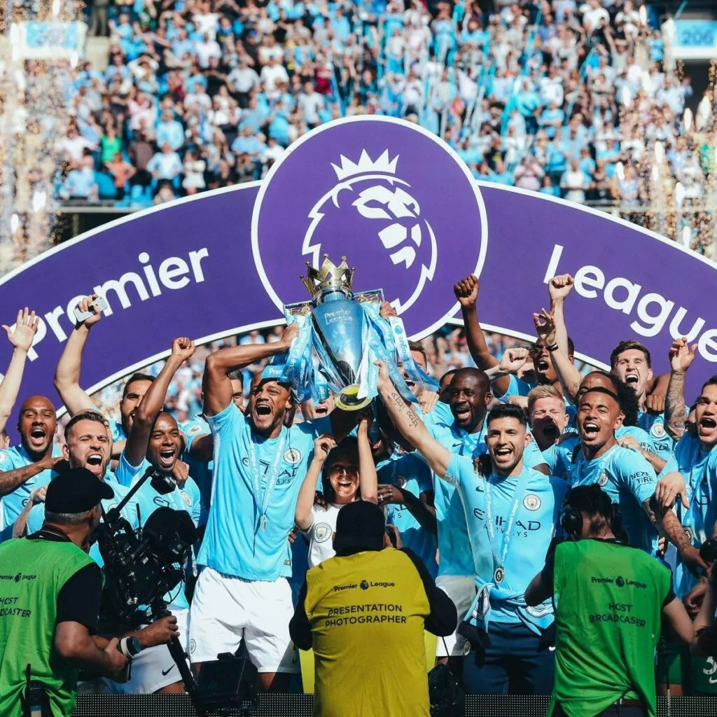 Equipe do Manchester City levantando a taça da primeira premier league de Pep Guardiola pelo time