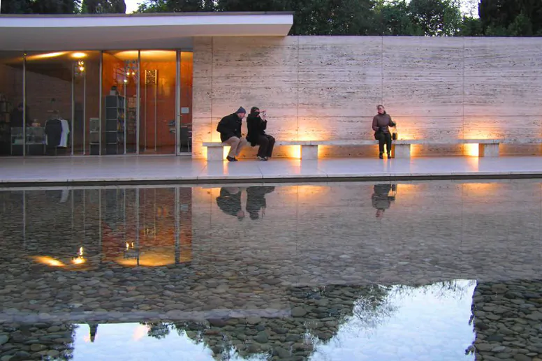 Pessoas sentadas em um longo banco no Pavilhão de Barcelona