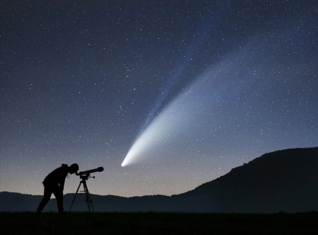 Silhueta de homem observando céu estrelado com um telescópio