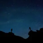 Silhueta de duas pessoas diante de um céu estrelado