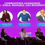Foto mostra três pessoas em palco falando sobre transição energética.