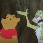 A imagem aprsenta o Ursinho Pooh, com um sorrriso tímido, e o Coelho, com expressão aflita, ambos olhando parea cima da animação da Disney de 2011