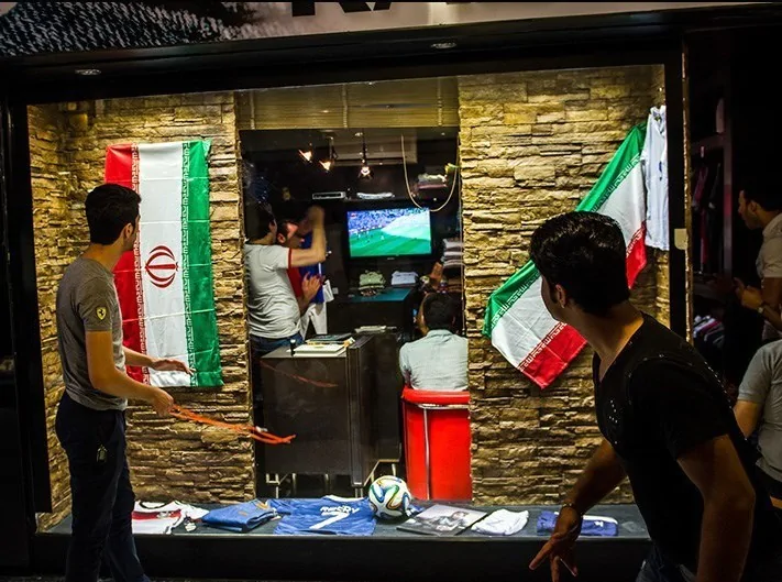 Torcedores assistindo jogo do Irã em um local com bandeiras do país