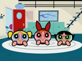 A imagem mosrra as Meninas Superpoderosas deitadas, como se estivessem assistindo televião, em um tapete branco localizado em uma sala de estar.