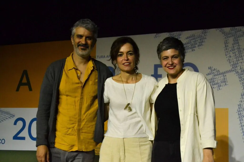 A imagem mostra Chico Mattoso, Maria Brant (escritores) e Patrícia Ditolvo (mediadora da mesa) abraçados posando para foto na Feira do Livro 2026