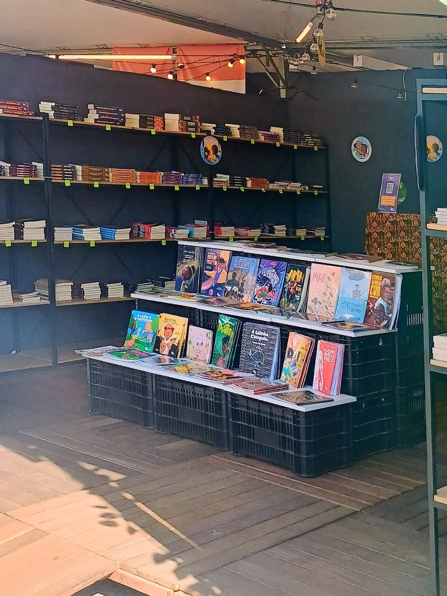 Livros infantis dispostos em caixotes e prateleiras no tablhado literário da Feira do LIvro 2026
