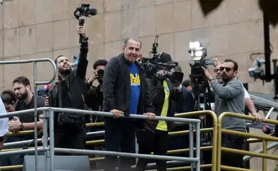 Homem branco em cima de uma carro de passeata com câmeras