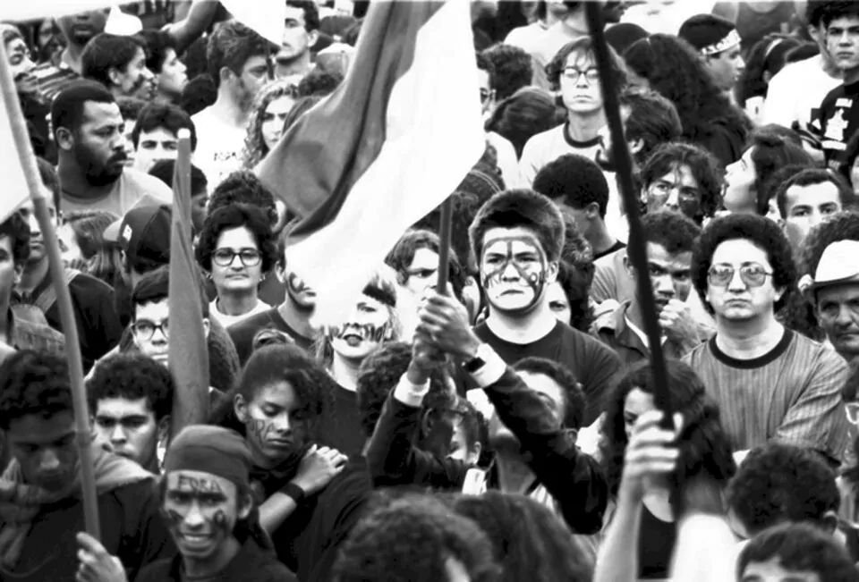 Pessoas em foto preto e branco num protesto segurando bandeiras e com símbolos hippies