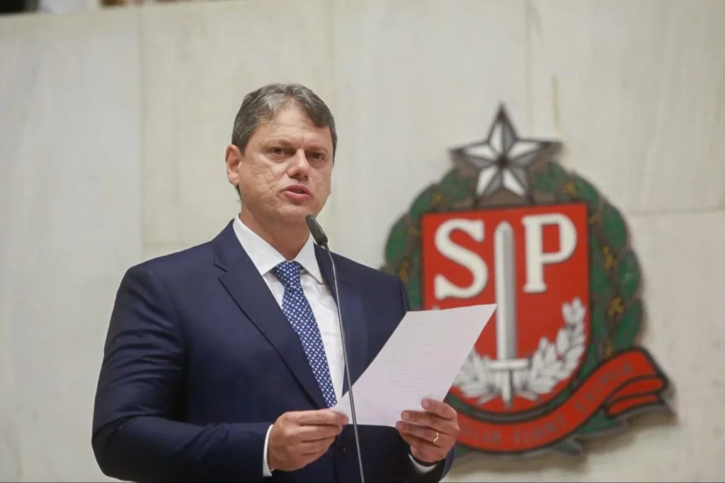 Homem branco de terno azul falando ao microfone