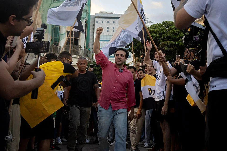 Homem branco de camisa vermelha com o punho levantado